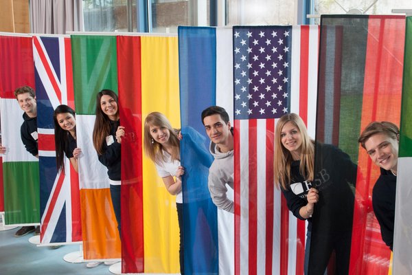 Students posing behind the flags of countries  of the partner universities of ESB Business School.