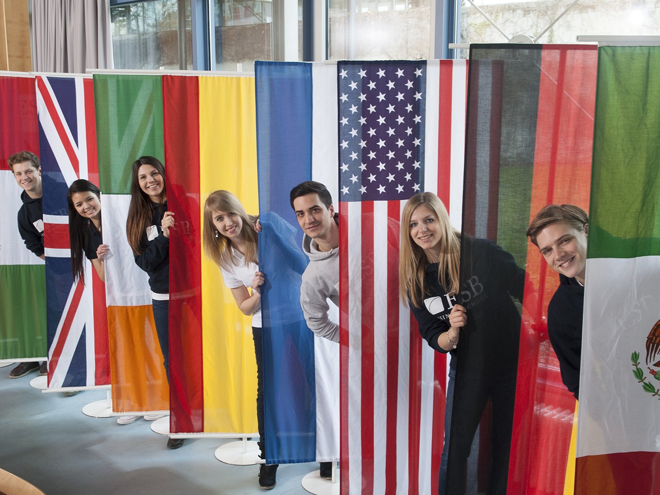 Students posing behind the flags of countries  of the partner universities of ESB Business School.