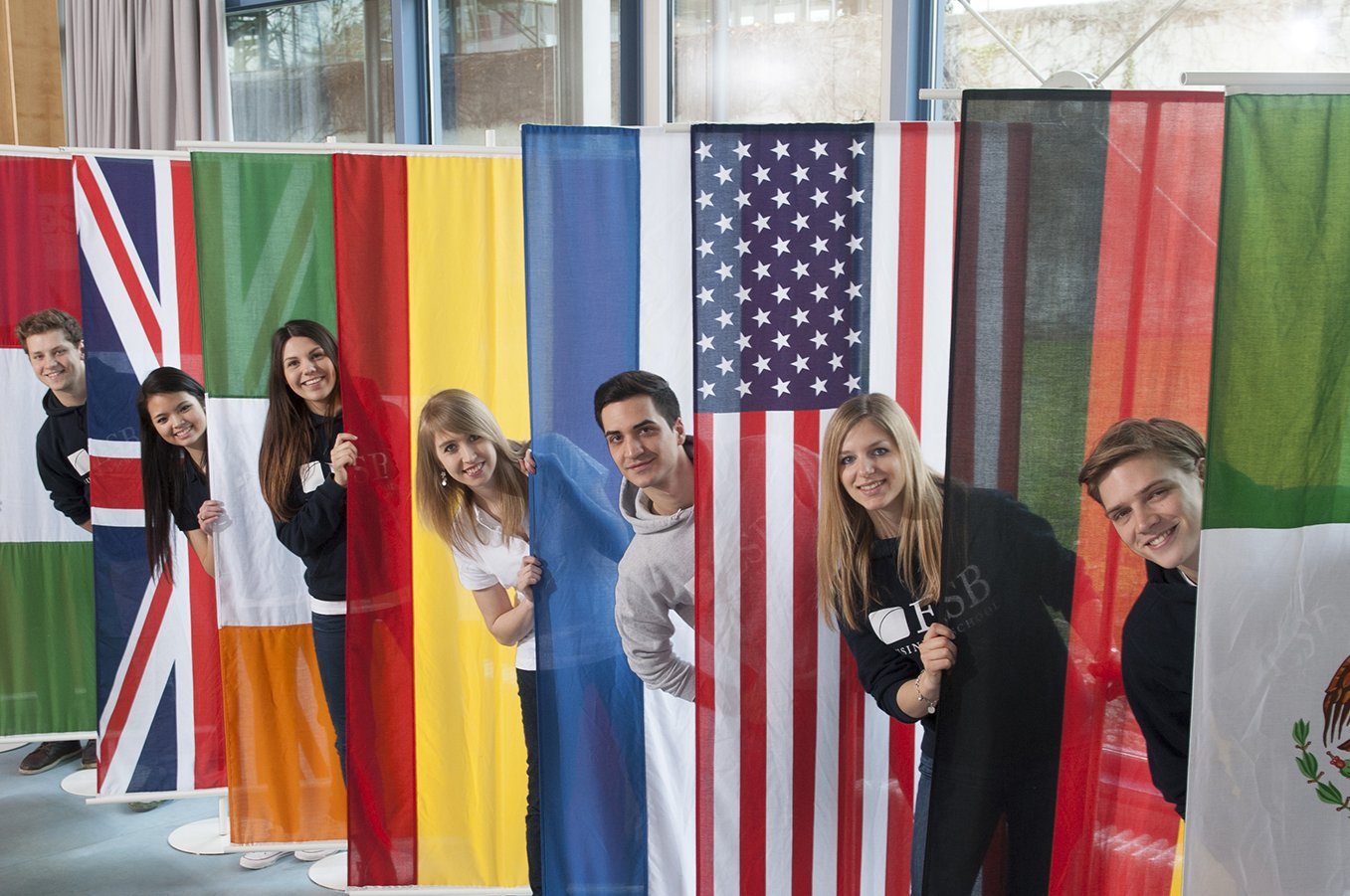 Students posing behind the flags of countries of the partner universities of ESB Business School.