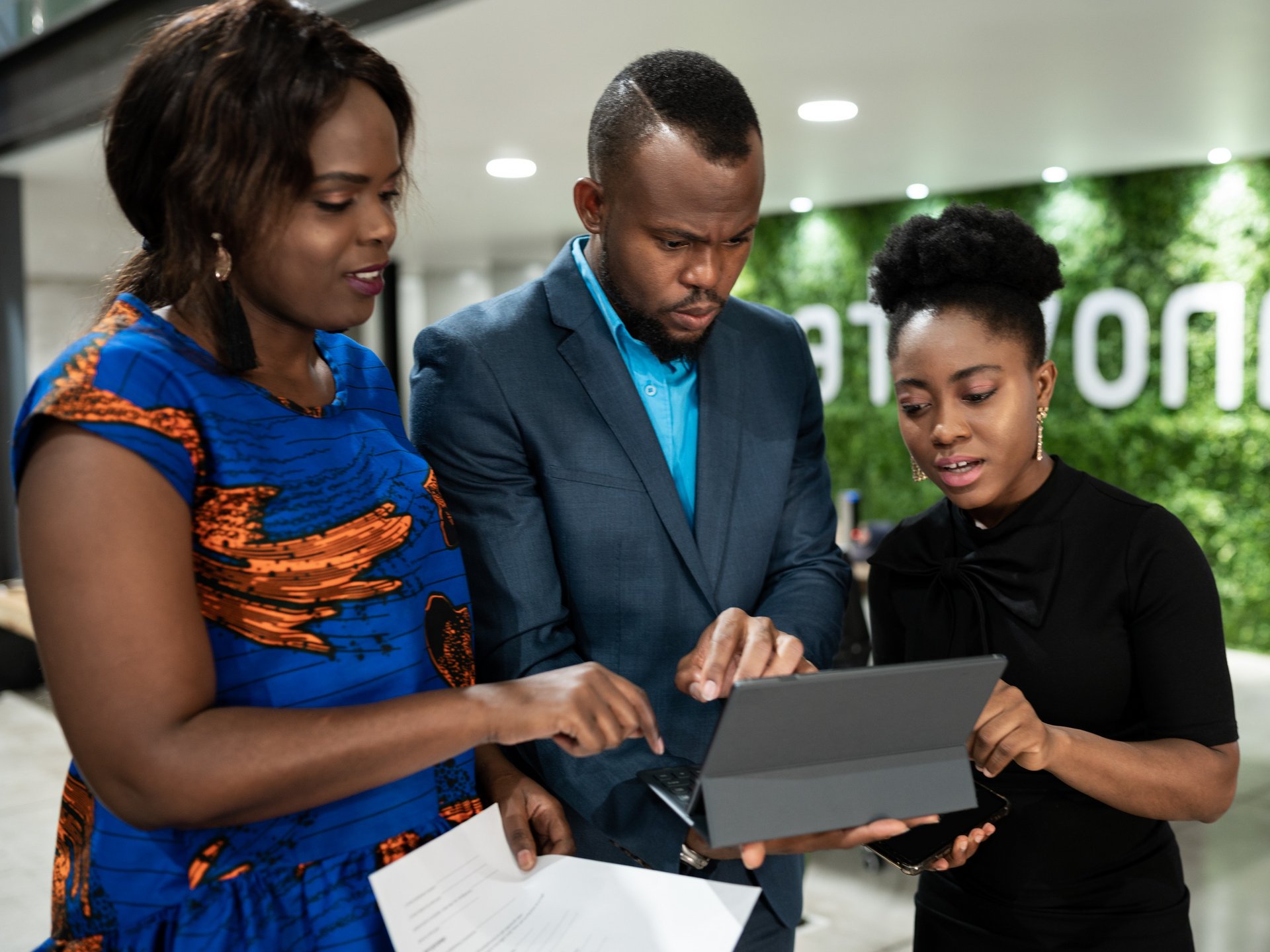 Business environment: 3 people are looking into a notebook, a woman pointing out a detail