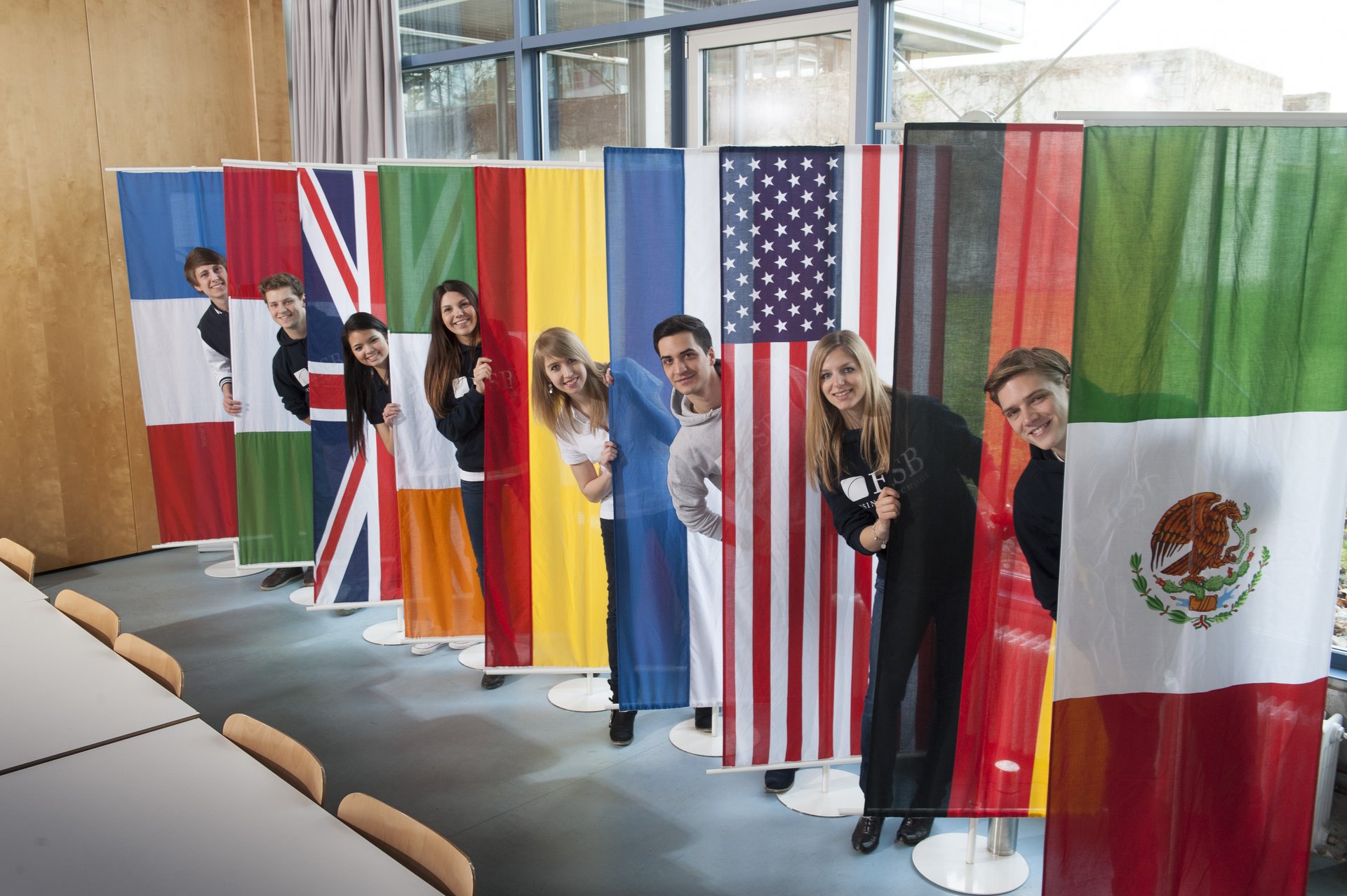 Students posing behind the flags of countries  of the partner universities of ESB Business School.