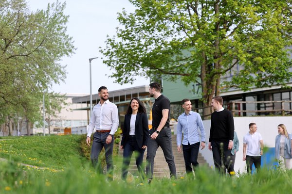 Studierende auf dem begrünten Campusgelände