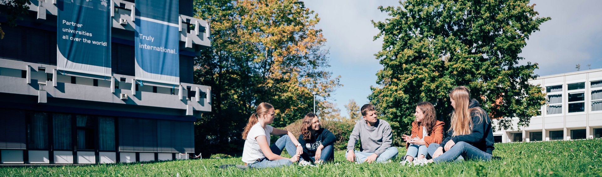 Studierende sitzen auf einer Wiese vor der ESB Business School.