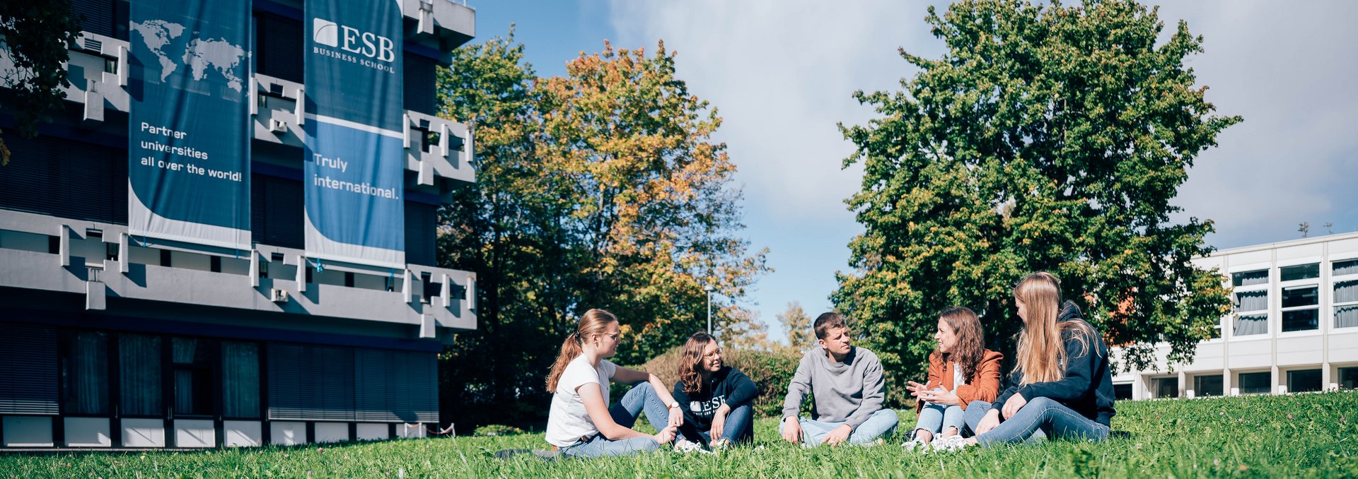 Studierende sitzen auf einer Wiese vor der ESB Business School.