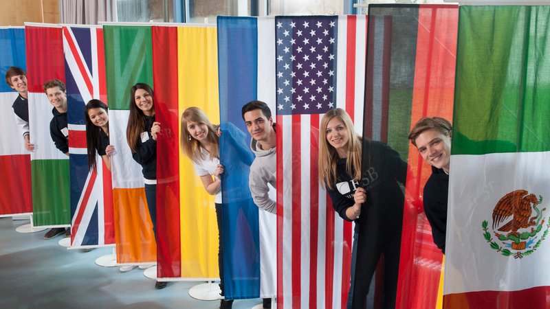 Students posing behind the flags of countries  of the partner universities of ESB Business School.