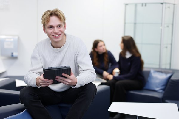 Sitzender Student mit einem Tablet in den Händen