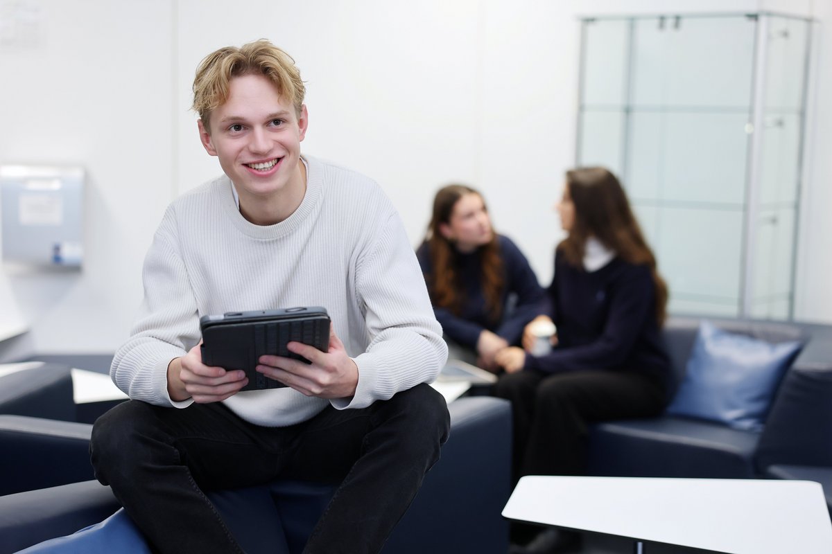 Sitzender Student mit einem Tablet in den Händen